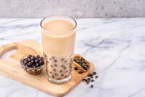 populär taiwan drink - bubble milk tea med tapioka pärlboll i dricksglas på marmorvit bord träbricka bakgrund, närbild, kopieringsutrymme foto