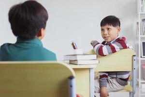 asiatisk student pratar med sin vän i ett klassrum foto