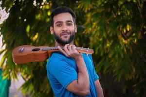 pojke med ukulele ett musikinstrument stilig indisk musikerbild foto