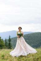 porträtt av en vacker brud i bergen. flickan håller en bröllopsbukett i händerna. foto
