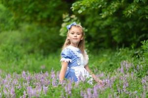 porträtt av en liten söt flicka klädd som alice. stiliserad fotografering i naturen. foto