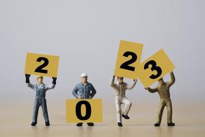 miniatyrarbetare som visar 2023 på gul tavla för förberedelse god jul och gott nytt år koncept. foto