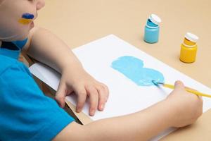 gula och blå färger och barnhänder med en pensel vid bordet. ritningar av ukrainska barn koncept foto