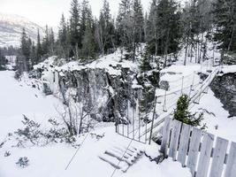 hängbro med snö vid vattenfallet rjukandefossen, hemsedal, norge. foto