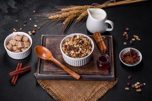 välsmakande hälsosam frukost med flingor, granola, choklad, mjölk och sylt på en mörk betongbakgrund foto