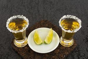 två guld tequilashots med lime foto