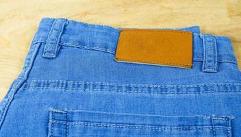 briljant läderämne på baksidan av blå jeans, brun etikett på linningen på jeans för att bära bokstäver, denimbakgrundsetikett kläder till salu, taggar helt ny byxetikett, foto