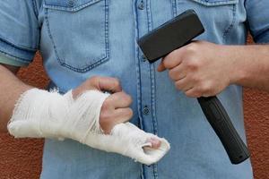 en man med en bandagerad hand och en hammare foto