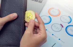 affärsman håller bitcoin-mynt ur plånboken. virtuell valuta. kryptovaluta. nya virtuella pengar. foto