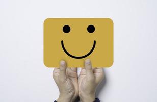 hand som håller och ger gult kort med ett leende ansikte för positivt tänkande och utmärkt kundnöjdhet och utvärderingskoncept. foto