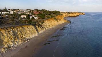 flygdrönare syn på människor på stranden under en vacker solnedgång. fantastiska livfulla färger. algarve, portugal. klart vatten. helgdagar och semestrar. resor och äventyr. nomadliv. foto