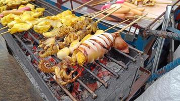 bbq bläckfisk på en pinne. grillad smörad färsk bläckfisk redo att äta gatumat i thailand foto