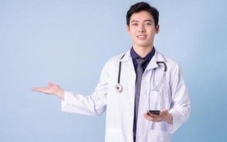 porträtt av ung asiatisk manlig läkare på blå bakgrund foto