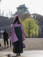bakifrån av japansk kvinna i hakama kimono med suddig slottsbakgrund foto