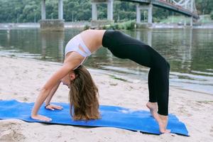 ung vältränad kvinna i sportkläder i olika yoga-asanas utomhus på stranden vid floden. yoga och sport koncept foto
