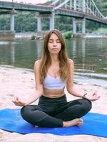 ung vältränad kvinna i sportkläder i olika yoga-asanas utomhus på stranden vid floden. yoga och sport koncept foto