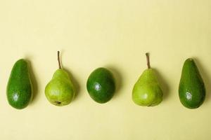 platt låg av diverse färska gröna frukter avokado och päron på gul bakgrund foto