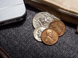 amerikanska dollarmynt placerade utanför plånboken med smartphone. foto