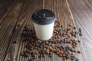 papper kaffekopp med kaffebönor på träbord foto