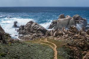 vågorna slår mot kusten vid capo testa sardinien foto