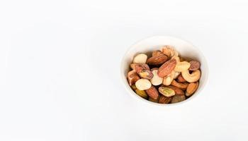 koncept, trail mix dag. trail mix i en kopp placerad på ett vitt golvbord. närbild. kopiera utrymme till vänster för design eller text. vit bakgrund. foto