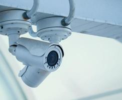 CCTV-kamera på ljusblå himmel bakgrund, koncept. 24 timmars bevakning dag och natt foto