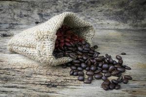 kaffebönor i säckväv påse på träbakgrund foto