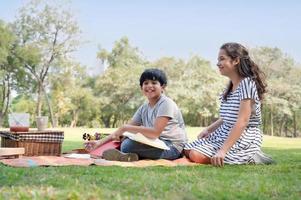 en halvthailändsk indisk pojke och en halvthailändsk-europeisk flickvän som lär sig utanför skolan i parken foto