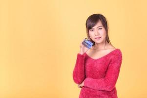 en vacker asiatisk kvinna är glad och tror att hon kommer att spendera med många av sina kreditkort foto