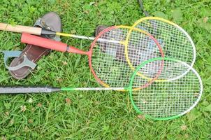 kvinnors sommarsandaler och badmintonracketar på gräset, ovanifrån. familjesporthelg eller sportspel för hela familjen i parken, sommarkoncept. foto