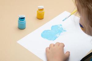 gula och blå färger och barnhänder med en pensel vid bordet. ritningar av ukrainska barn koncept foto