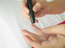 kvinna som använder lansett på fingret, diabetestest foto