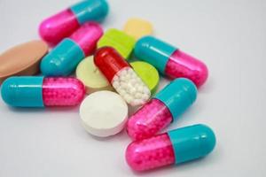 färgade piller, tabletter och kapslar på vit bakgrund foto