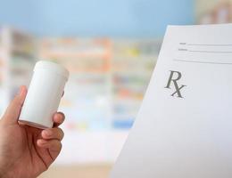 kvinnlig farmaceut med recept och medicinflaska på apoteket foto