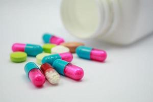 färgade piller, tabletter och kapslar på vit bakgrund foto
