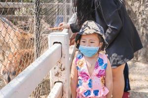 bedårande barnflicka som bär medicinsk ansiktsmask för att förhindra symtom på covid-19-pandemisjukdom under resetur med mamma eller familj. foto