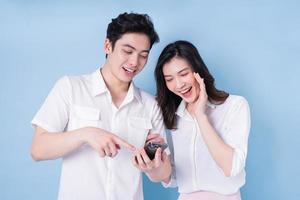 bild av unga asiatiska par som använder smartphone på blå bakgrund foto
