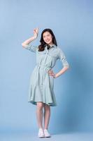 full längd bild av ung asiatisk kvinna som bär klänning på blå bakgrund foto