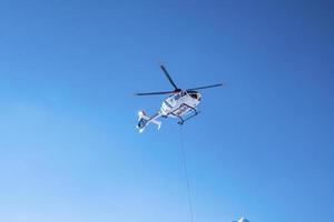 polishelikopter flyger ovanför mot blå himmel på solig dag foto