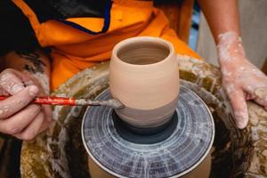 krukmakare arbetar på krukmakare hjul med lera. process för att göra keramiska serviser i keramikverkstad. foto
