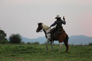 cowboy till häst mot en vacker solnedgång, cowboy och häst vid första ljuset, berg, flod och livsstil med naturligt ljus bakgrund foto