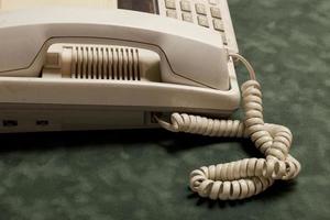 vintage telefon med lur och telefonsvarare på grön sammet, luren ligger bredvid. foto
