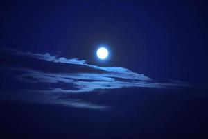 en vacker stor måne på en mörkblå himmel med moln. foto