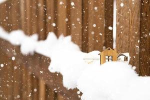 nyckeln till huset på ett trästaket på vintern i snön. en present till nyår, jul. bygga, designa, projektera, flytta till nytt hus, belåna, hyra och köpa fastigheter. kopieringsutrymme foto