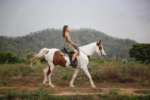 ung kvinna med sin häst i kvällssolnedgångsljus. utomhusfotografering med modell flicka. livsstil humör foto