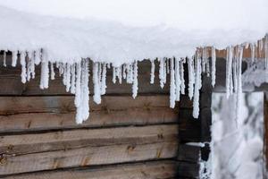 istappar under snötak av en timmerstuga på vintern i Finland. foto