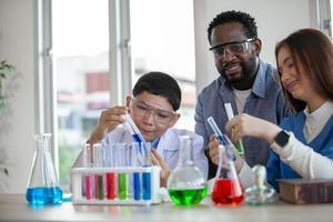 elever blandar kemikalier i bägare. entusiastisk lärare förklarar kemi för barn, kemistudent visar nytt experiment för lärare i naturvetenskap foto