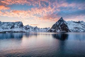 bergskedja med fluffiga färgglada moln i havet vid solnedgången foto