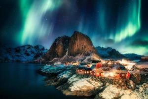 norrsken, norrsken över berg med fiskeläge på kusten vid hamnoy, lofoten öarna foto