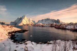 soluppgång på snöiga berg med skandinavisk by vid kusten på vintern foto